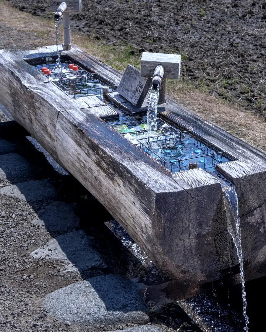 Water running into a long timber stock trough in a paddock